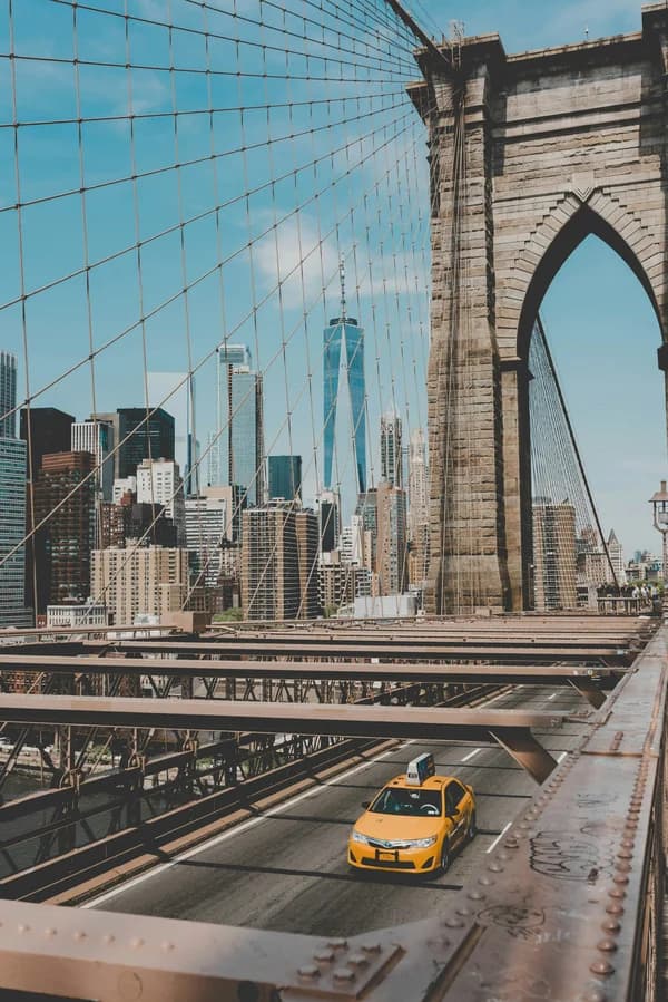 Brooklyn Bridge with NYC skyline and a yellow taxi