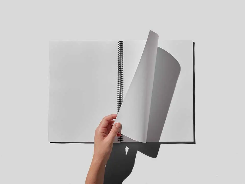 An employee leafing through a spiral bound instruction manual printing job by Thomas Group Printing