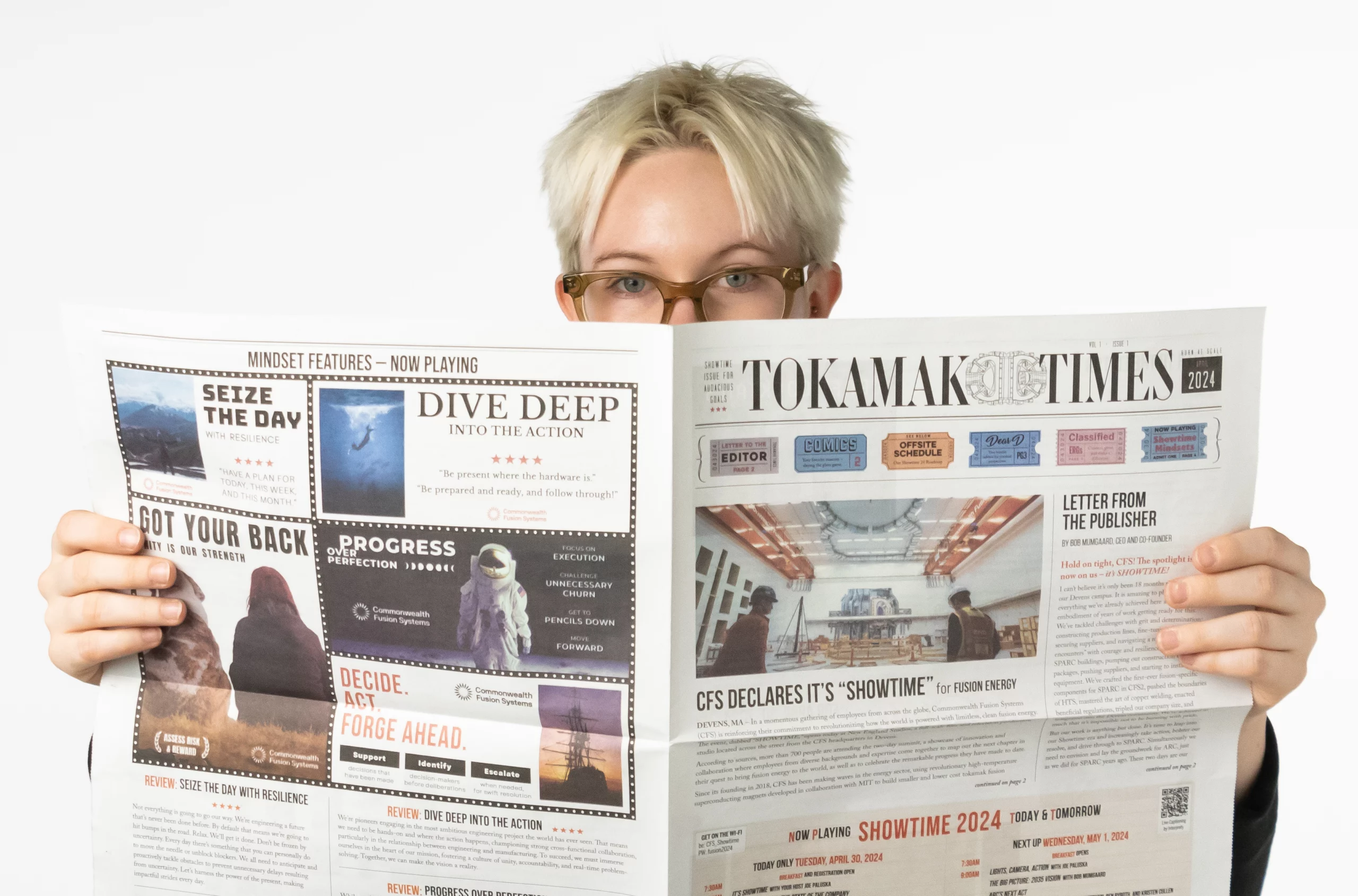 A person holds up an open tabloid size newspaper in front of them showing the size.