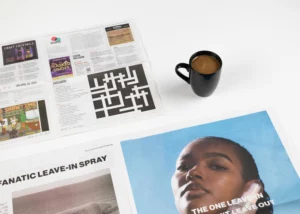 A folded broadsheet newspaper laying next to a folded tabloid newspaper showing their size differences.